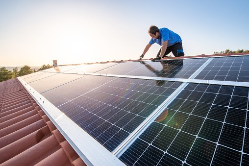 instalador fotovoltaico colocando placas solares sobre tejado